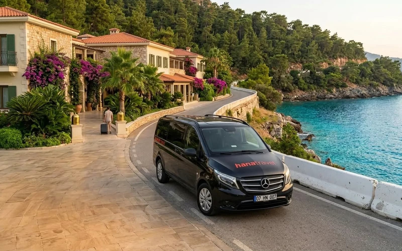 Black Hana Travel Vito driving along a sunny coast road above turquoise water on the Antalya Riviera — Antalya private transfer