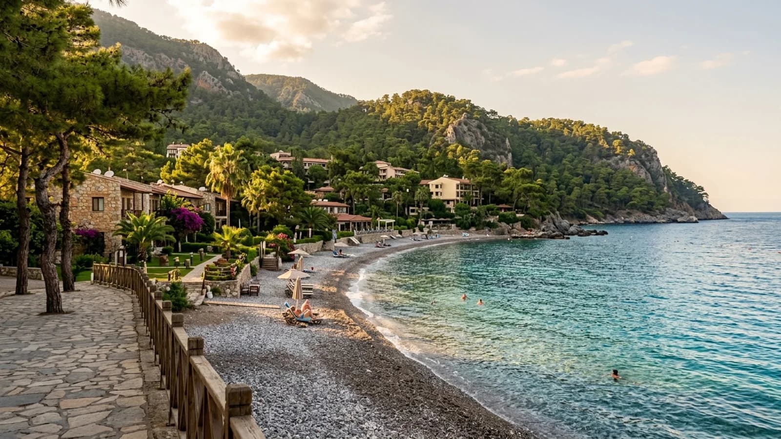 Scenic pebble cove and resort in Beldibi Limestone slopes covered in pines descend to a clear turquoise pebble cove with secluded hotels in Beldibi.