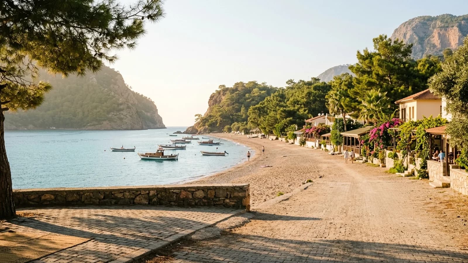 La baie paisible d'Adrasan Une baie abritée à Adrasan avec une longue plage, des caps boisés et quelques bateaux sur l'eau.