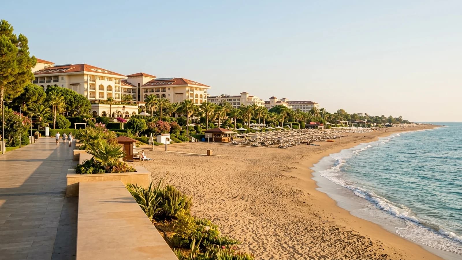 Sandy beach and resorts in Çolaklı A long sandy beach in Çolaklı with resort hotels, green gardens, parasols and gentle turquoise waves.